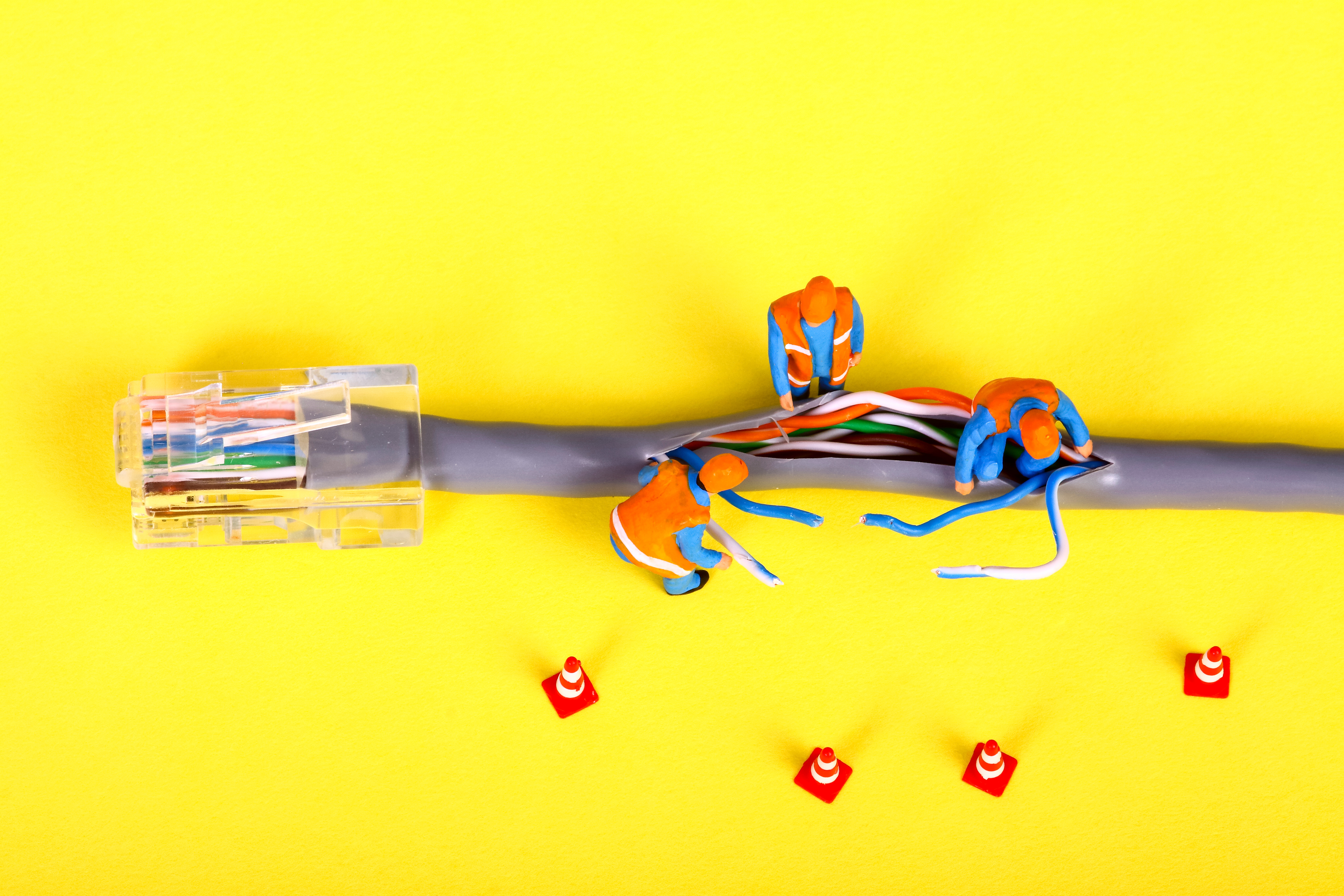 Conceptual image of miniature figure workmen investigating a fault on a broadband network cable